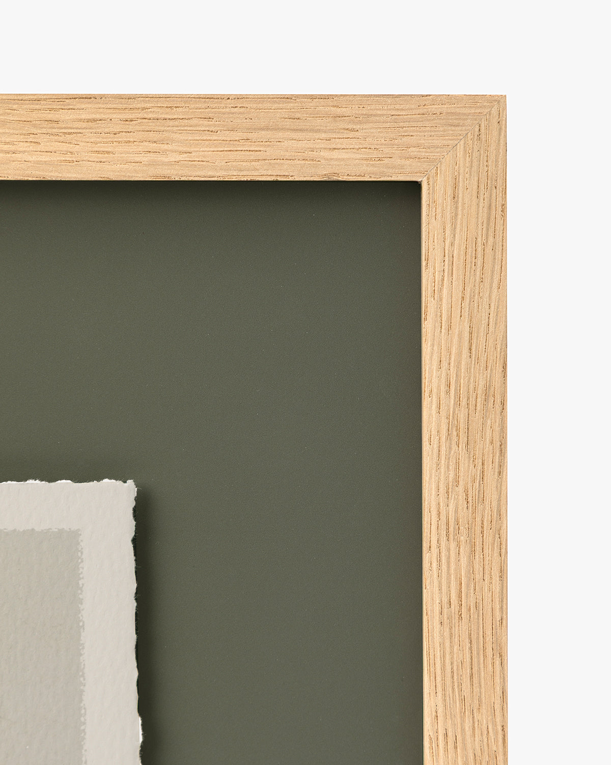 Close-up of the top right corner of the Cove in Charcoal frame, ideal for home decor, featuring a dark green matte background and a torn edge of white paper visible in the lower left corner, by McGee & Co.
