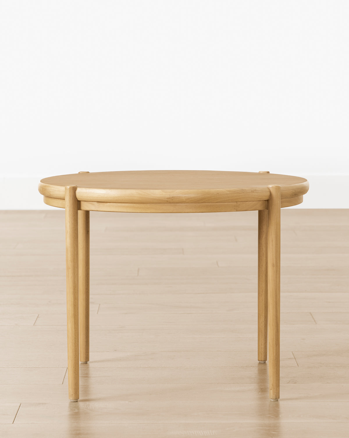 The Darcy Kids Table is a round, white oak kids table with four straight legs—ideal as a modern coffee or crafts table—shown on a light wood floor against a plain white wall, by McGee & Co.