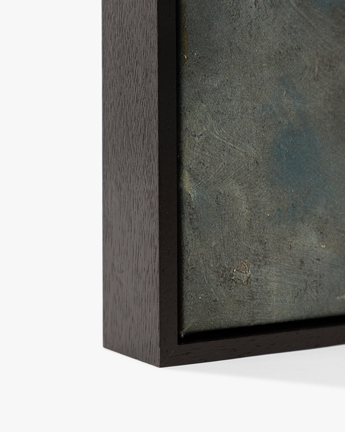 Close-up of the corner of a dark floater frame with an espresso finish, highlighting the edge and part of Dark Skies Ahead, a textured blue-gray abstract giclée canvas, by McGee & Co.