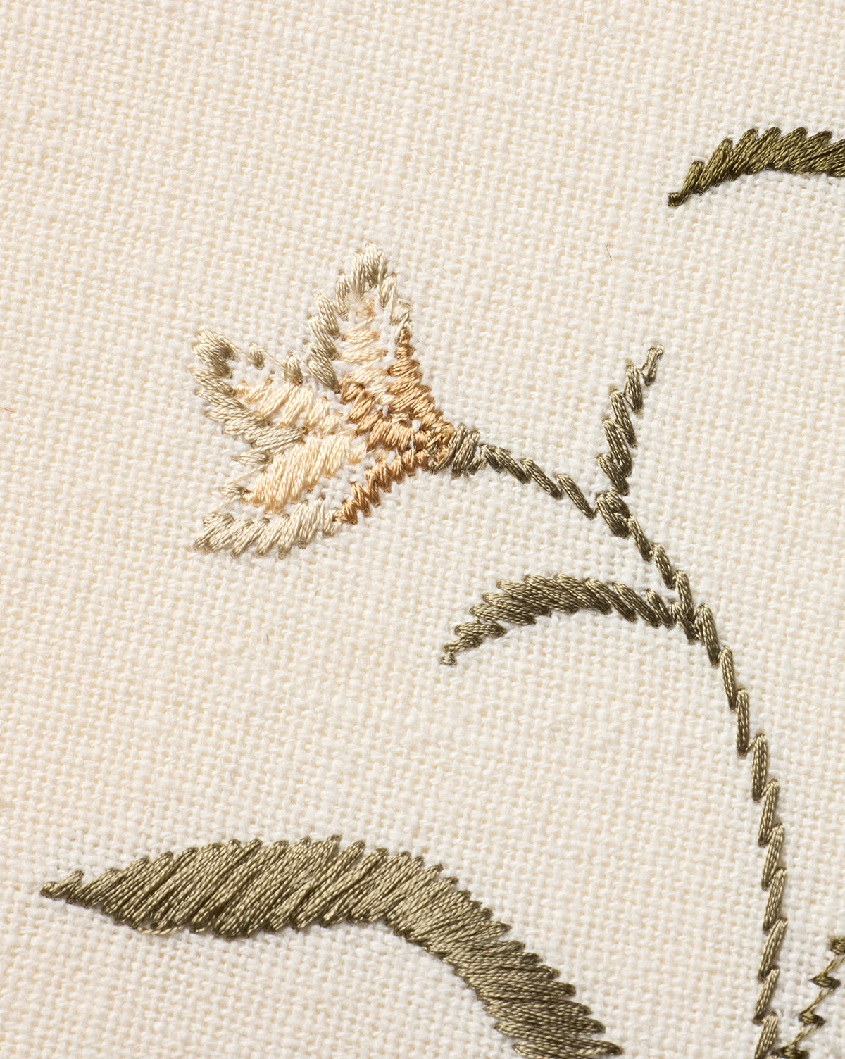 Close-up of Embroidered Pixie Flowers on beige fabric, showcasing a light orange and cream bloom with olive green leaves and stem. Intricate stitching makes it ideal as botanical wall art or unique cotton wall decor, by McGee & Co.