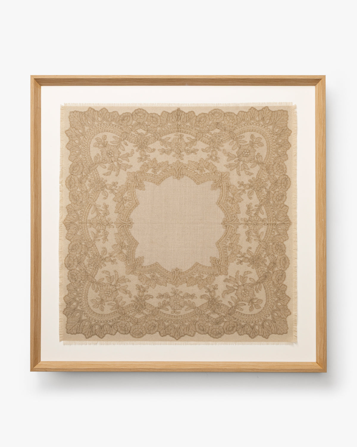 European Flare: Framed vintage lace handkerchief featuring detailed floral and leaf designs on white, bordered by a natural woodgrain frame for timeless European elegance, by McGee & Co.