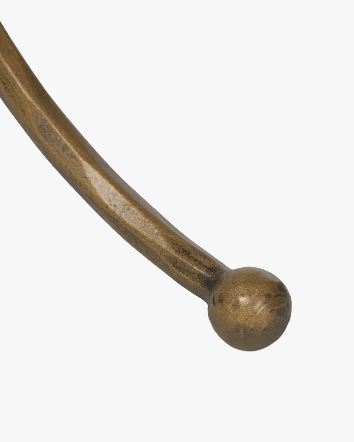 A close-up of the Fossil Marble End Tables curved, hammered aged brass metal leg ending in a round ball, set against a plain white background, by McGee & Co.