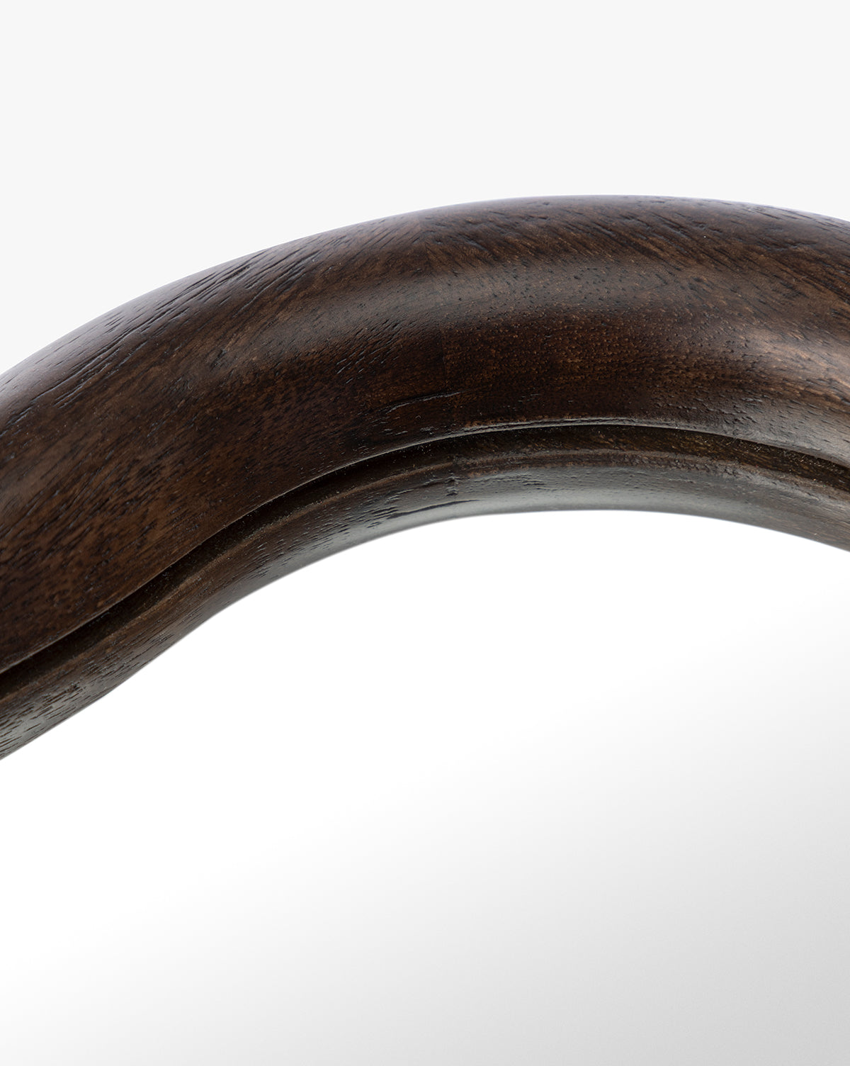 Close-up of the Freya Shelf Mirror featuring a dark polished wooden frame with a curved edge that reflects light on its smooth surface—an ideal accent for entryway decor, by McGee & Co.