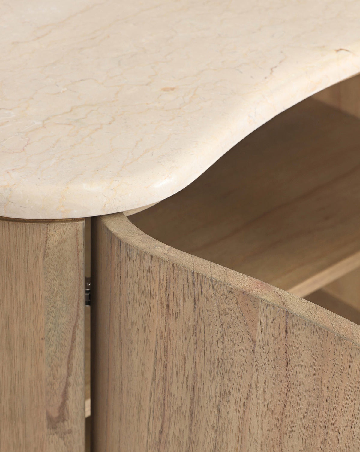 Close-up of the Gatlin Nightstand made from solid mindi wood, showcasing a curved edge and light, rounded marble top, by McGee & Co. A partially open cabinet door reveals convenient bedside storage inside.