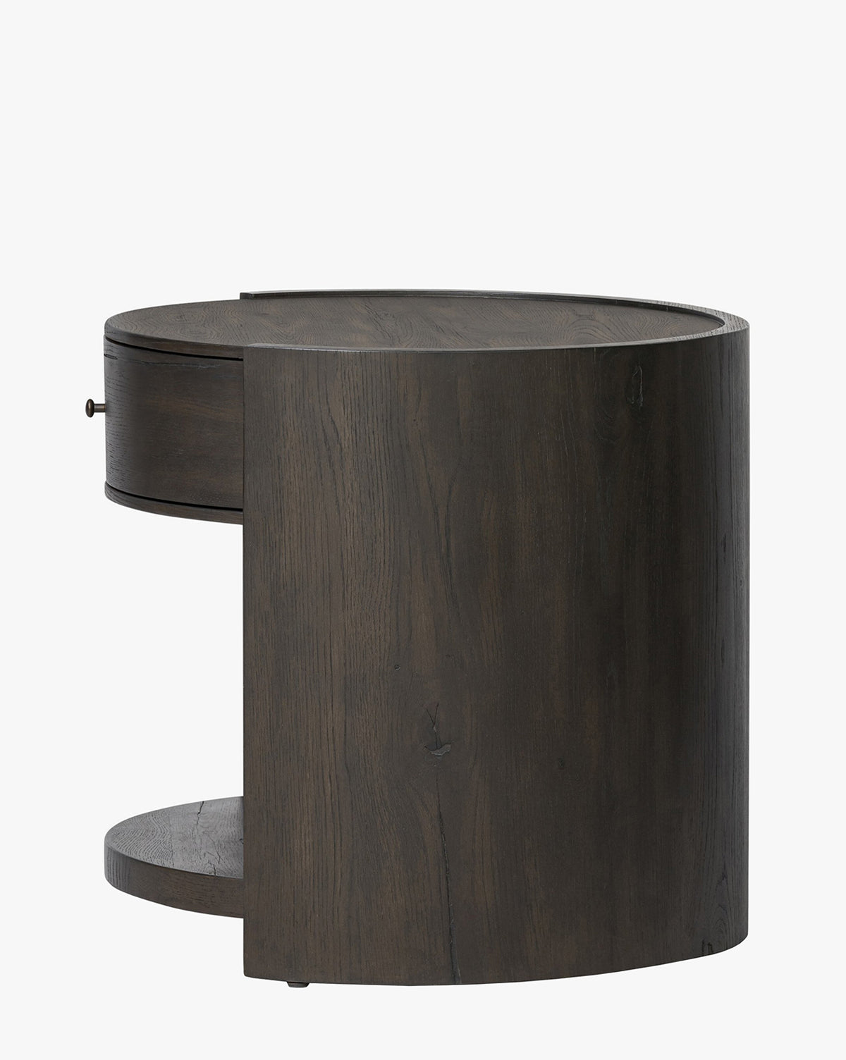 The Glenndon Oak Nightstand is a modern, round piece with a black-finished oak exterior, featuring one drawer and an open lower shelf, shown against a plain white background by McGee & Co.