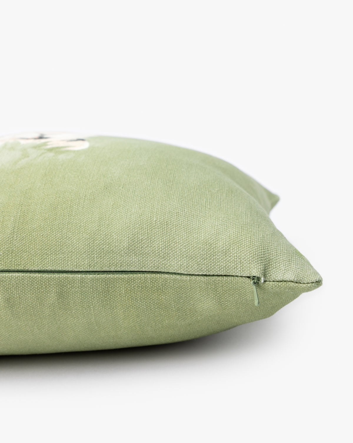 A close-up side view of the Holland Lop Pillow Cover shows its green textured fabric with an illustrated design and a visible zipper along the seam, set against a plain white background, by McGee & Co.