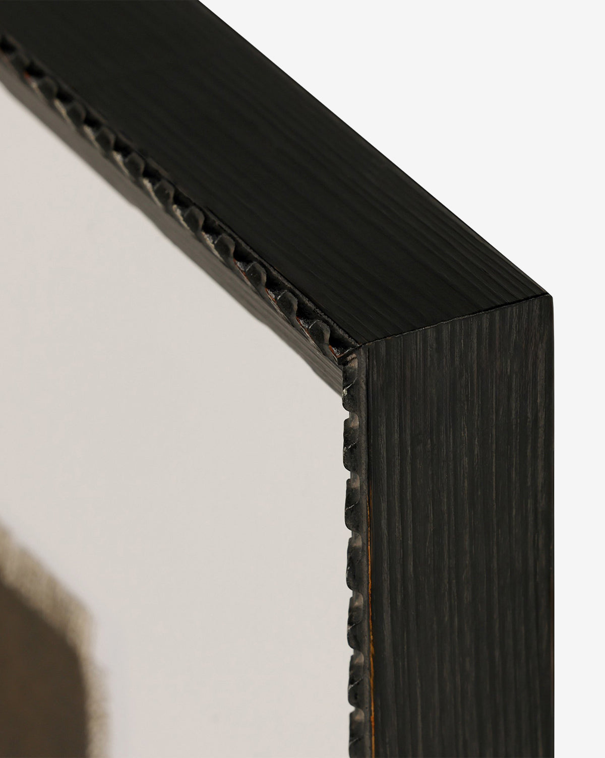Close-up of a dark Brimfield black frame corner with a ridged edge, displaying part of the layered oil painting Iron and Brass by Bethany Joseph against a plain white background, by McGee & Co.