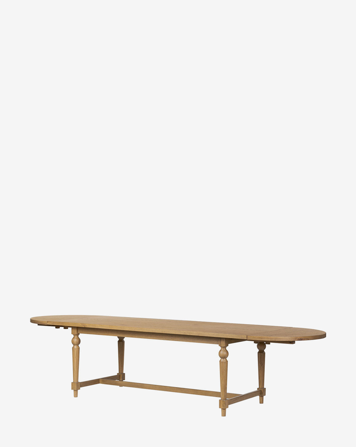 The Kyler Oak Extension Dining Table features a long, oval top, four turned legs, and a rectangular base support. Its natural wood finish highlights clean Scandinavian lines, shown here against a plain white background by McGee & Co.