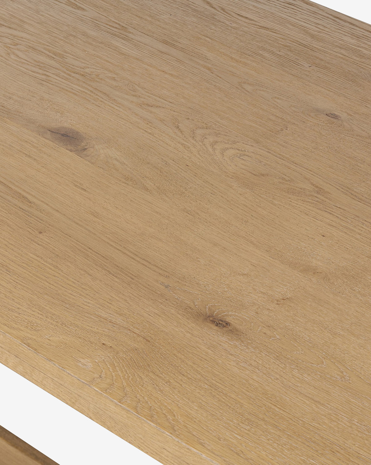 A close-up of the Kyler Oak Extension Dining Table showcases its natural light brown oak surface, featuring visible wood grain and knots that highlight its unique Scandinavian modern texture and pattern, by McGee & Co.