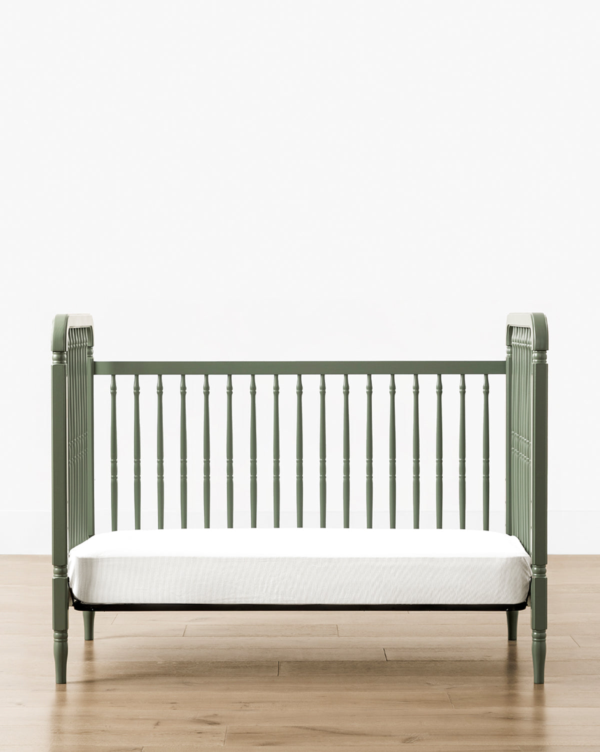 The Liberty 3-in-1 Convertible Spindle Crib comes in green with a white mattress, crafted from solid pine, and includes a Toddler Bed Conversion Kit to adapt as your child grows, by McGee & Co.