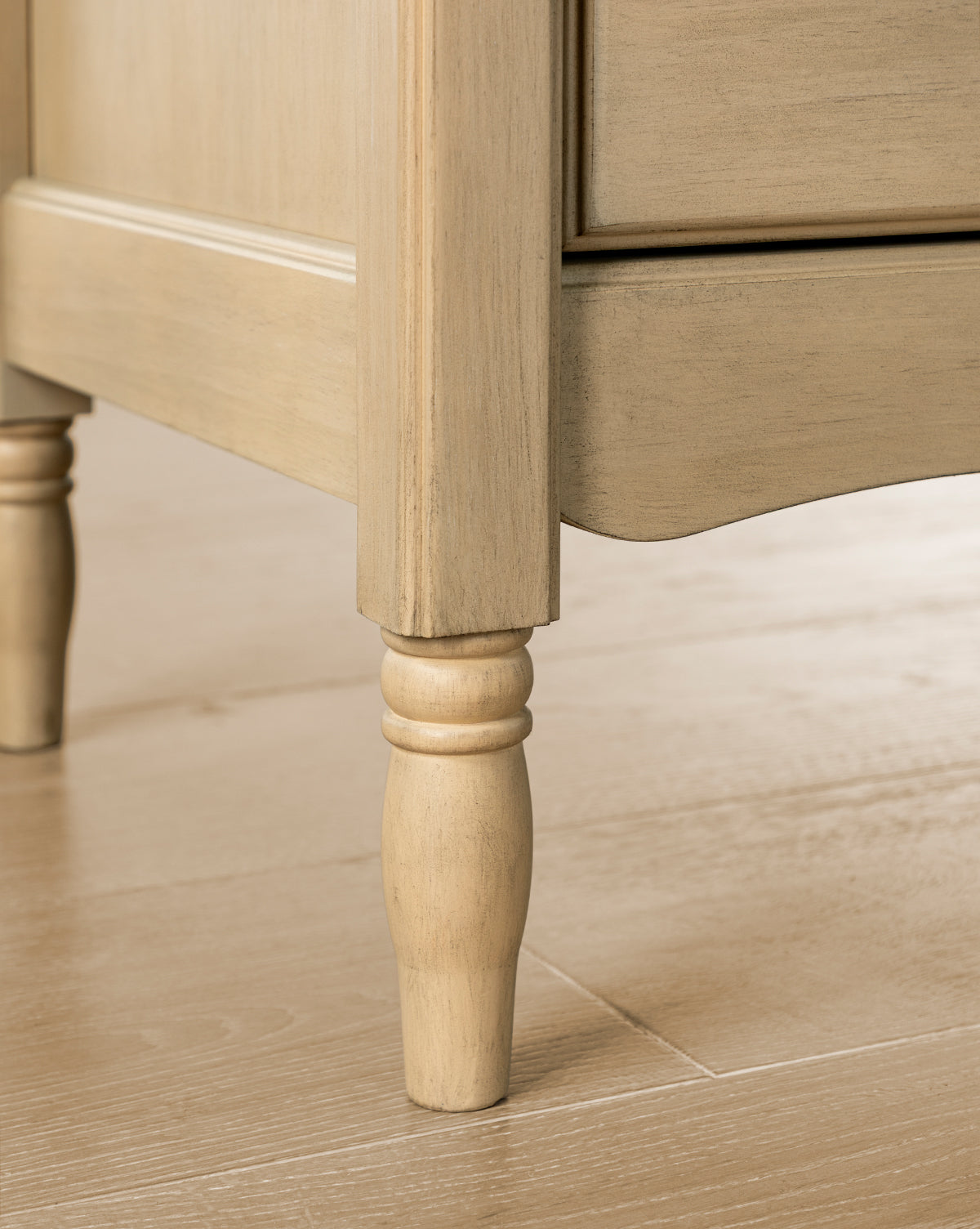 Close-up of the Liberty 6-Drawer Assembled Dresser, crafted from sustainable pine wood with a decorative turned leg and paneled side, shown on a light wood floor by McGee & Co.