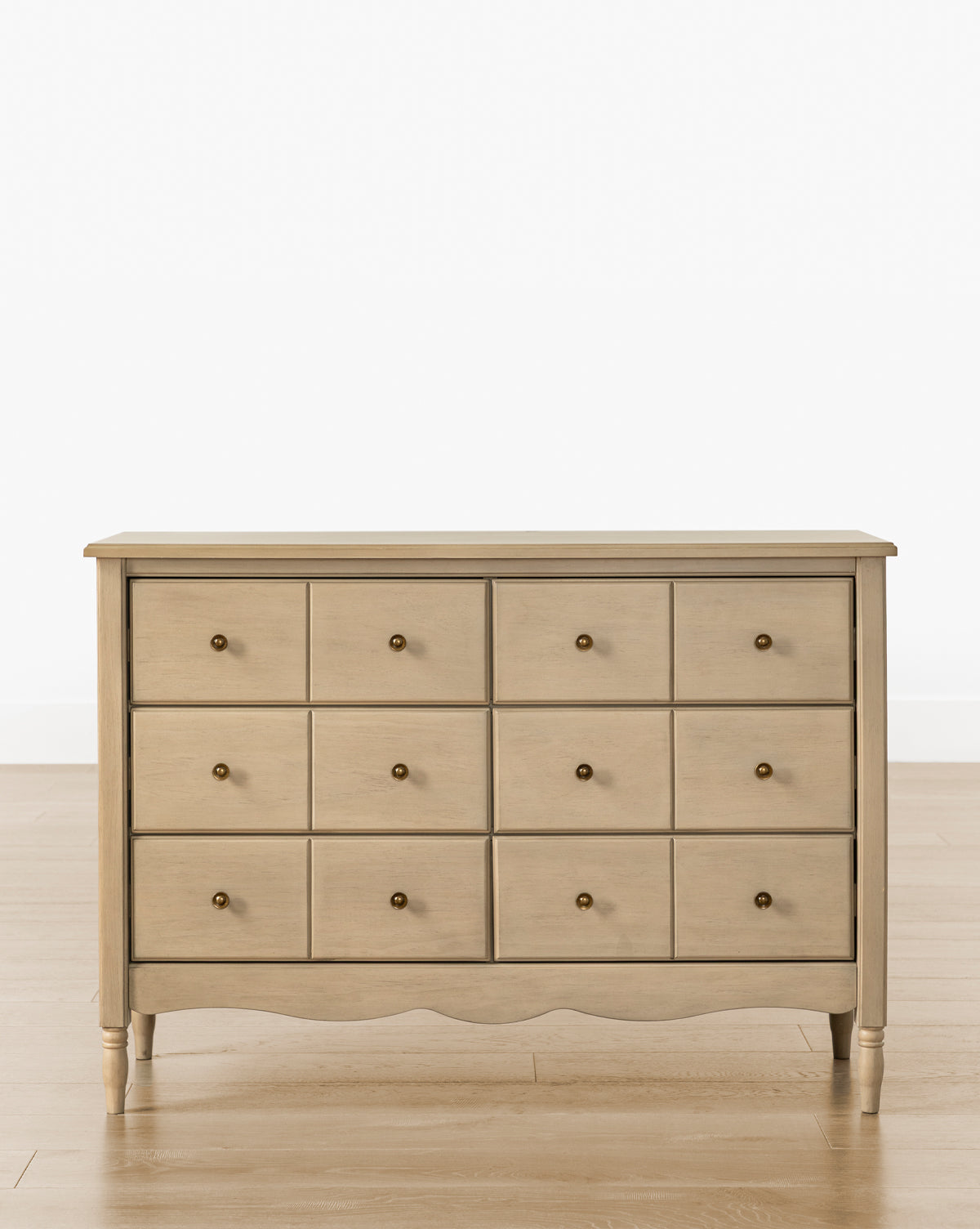 The Liberty 6-Drawer Assembled Dresser, made from sustainable pine, features six drawers with round metal knobs and stands on four short legs on a wooden floor against a plain white background, by McGee & Co.