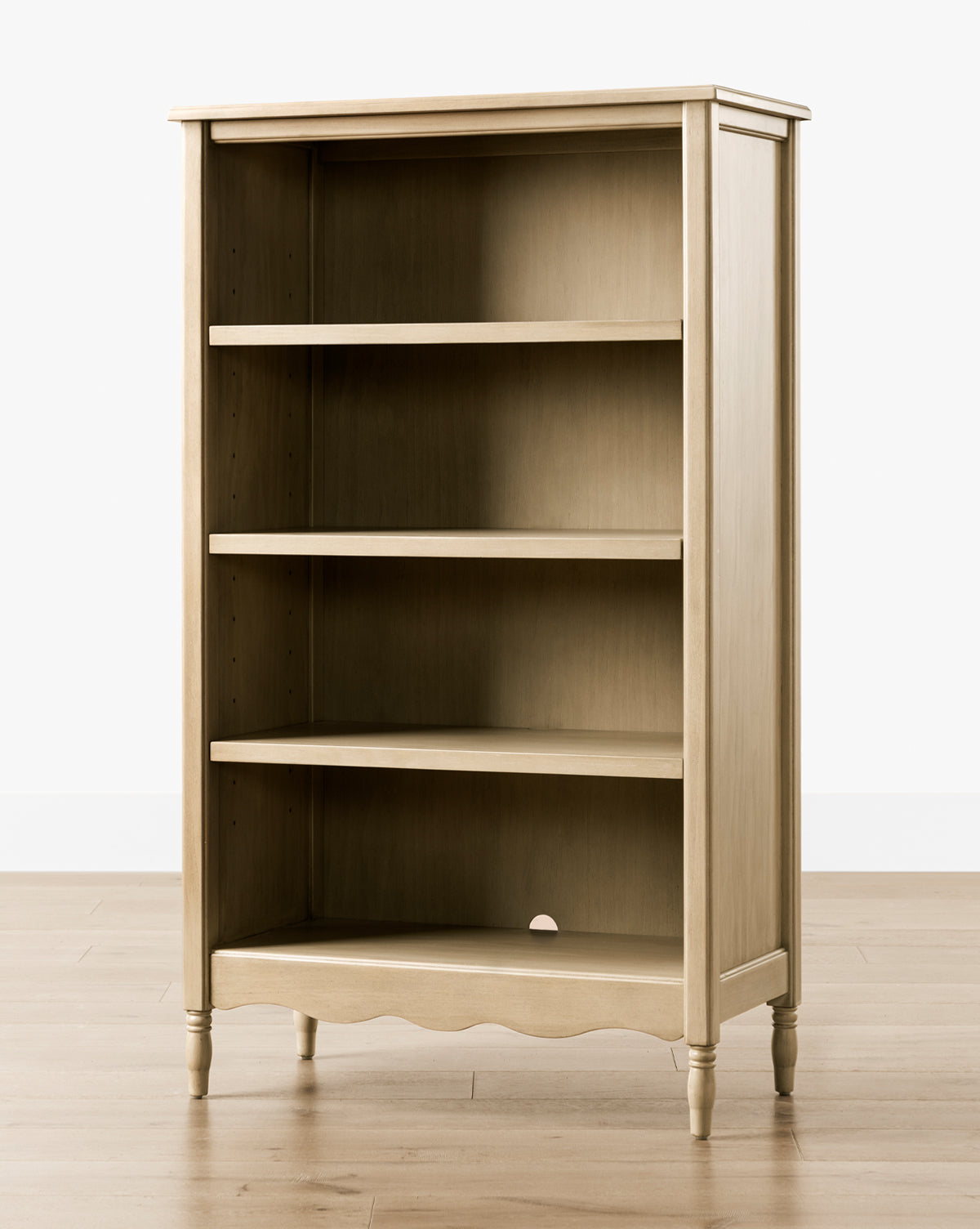 The Liberty Bookcase features a light wood finish, three shelves, and a scalloped base. Its classic design with turned legs adds timeless elegance, making it a stylish addition to any room, by McGee & Co.