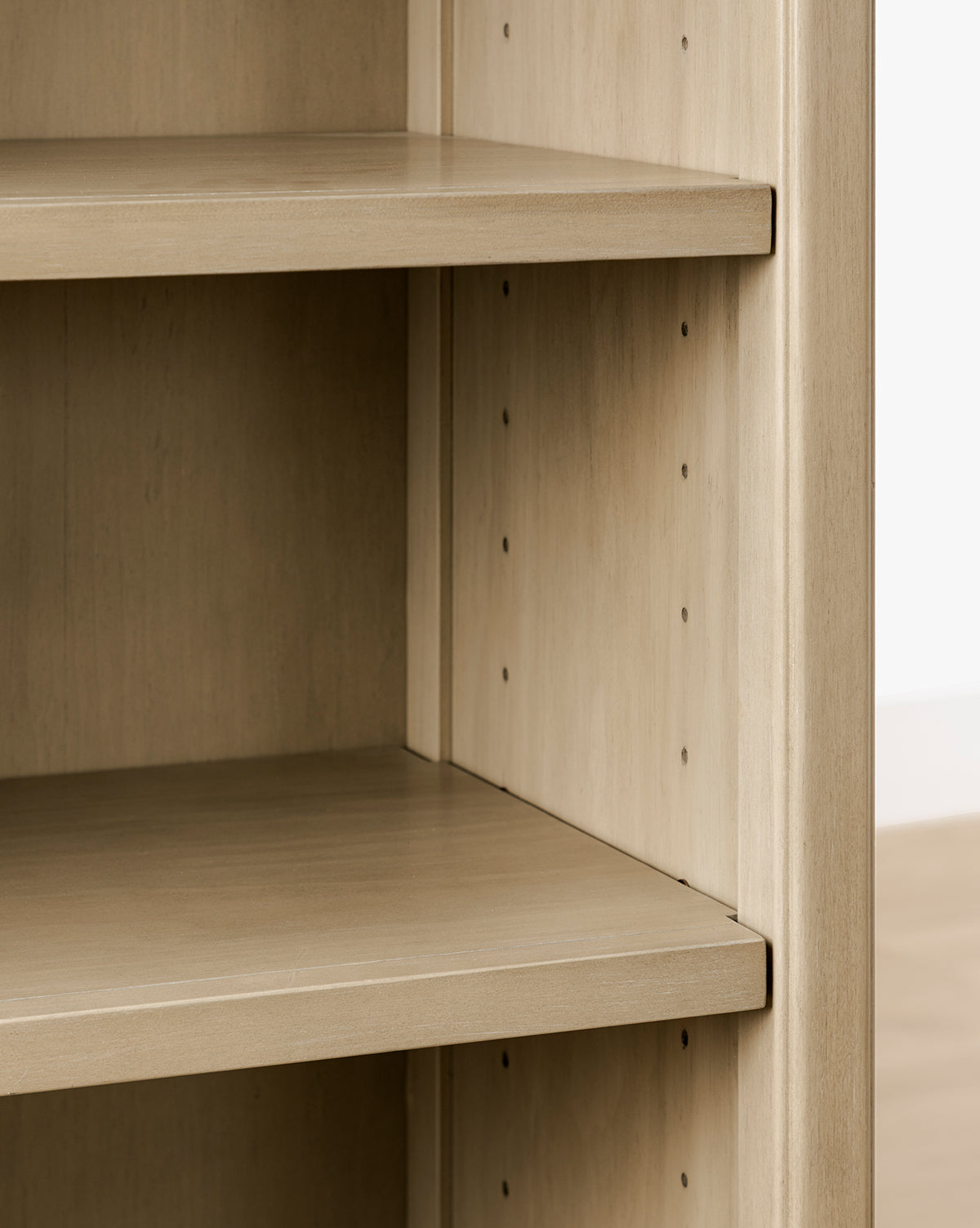 Close-up of the Liberty Bookcase, an empty wooden bookshelf with adjustable shelves, heirloom craftsmanship, light wood finish, and visible peg holes on the side panels by McGee & Co.