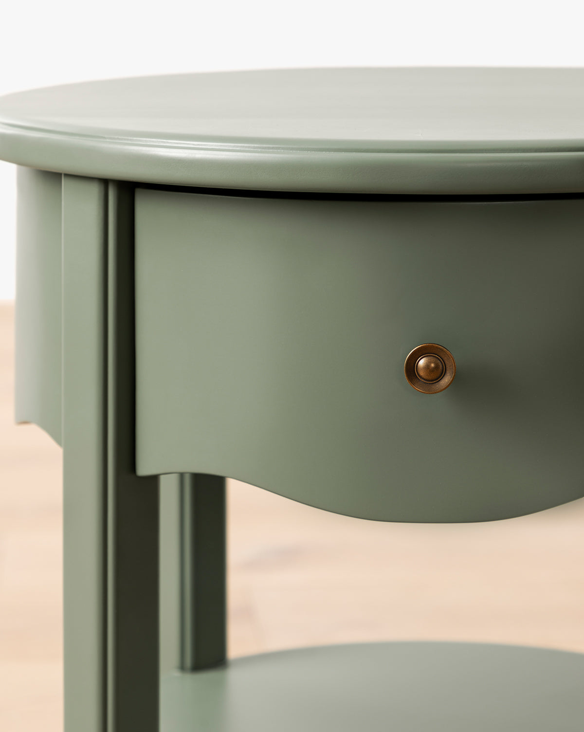 Close-up of the Liberty Nightstand—light green, round, with a single brass-knob drawer and open lower shelf on a light wood floor—perfect as a stylish GREENGUARD Gold Certified nursery nightstand by McGee & Co.