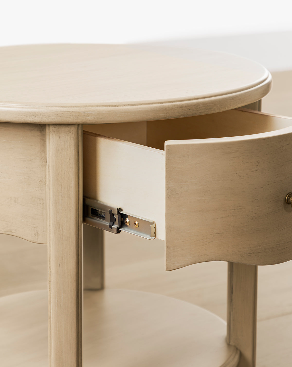 The Liberty Nightstand is a round wooden nightstand with a natural finish, featuring a curved drawer and metal sliding mechanism, offering both style and function as a nursery nightstand, by McGee & Co.