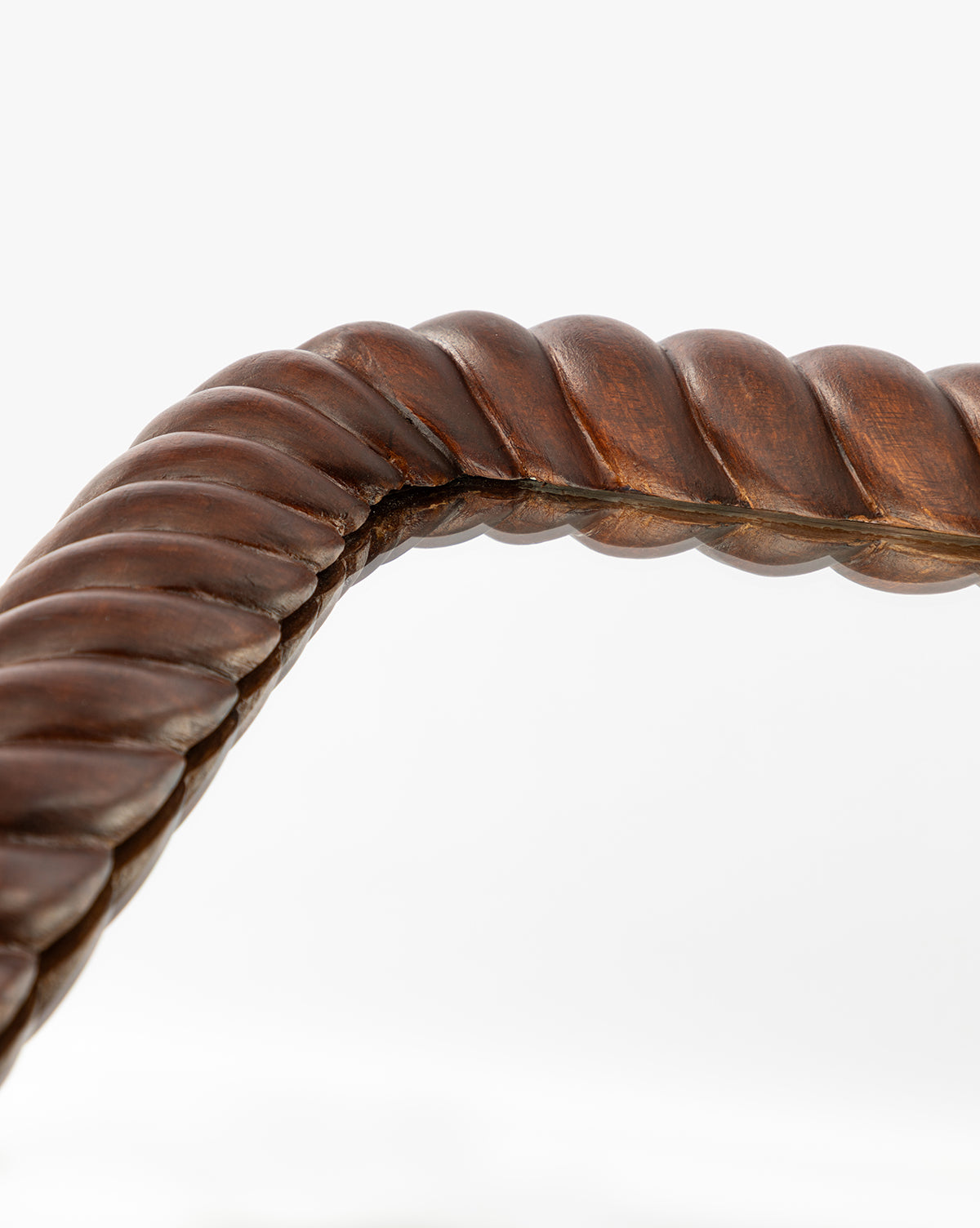 Detailed view of the Mayweather Wall Mirror’s dark red walnut frame, featuring a twisted rope design with a smooth, polished finish, forming an elegant corner against a white background, by McGee & Co.