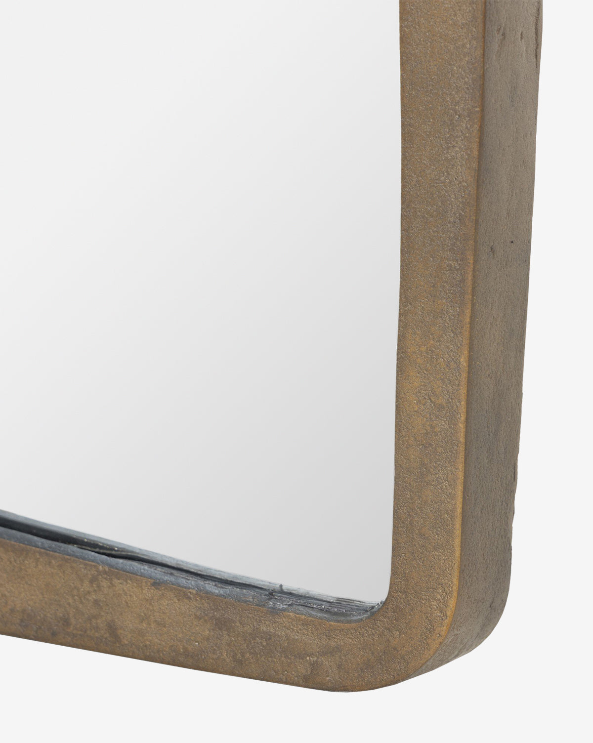 Close-up of the Penrod Floor Mirror’s corner, featuring a thick, rustic bronze-hued cast aluminum frame. The partially visible mirror reflects a white background—ideal as sculptural decor for any home, by McGee & Co.