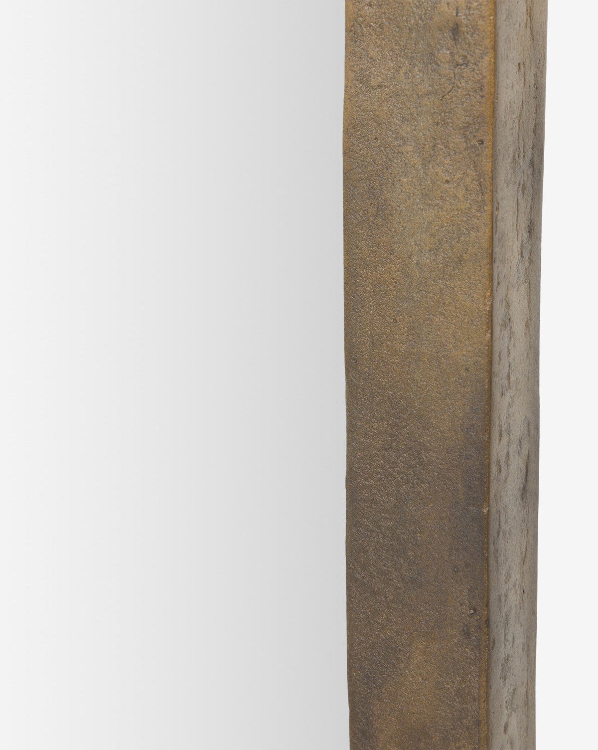 Close-up of the Penrod Floor Mirror, showcasing its thick, textured weathered gold or bronze-colored cast aluminum frame on the right and reflective surface on the left, by McGee & Co.