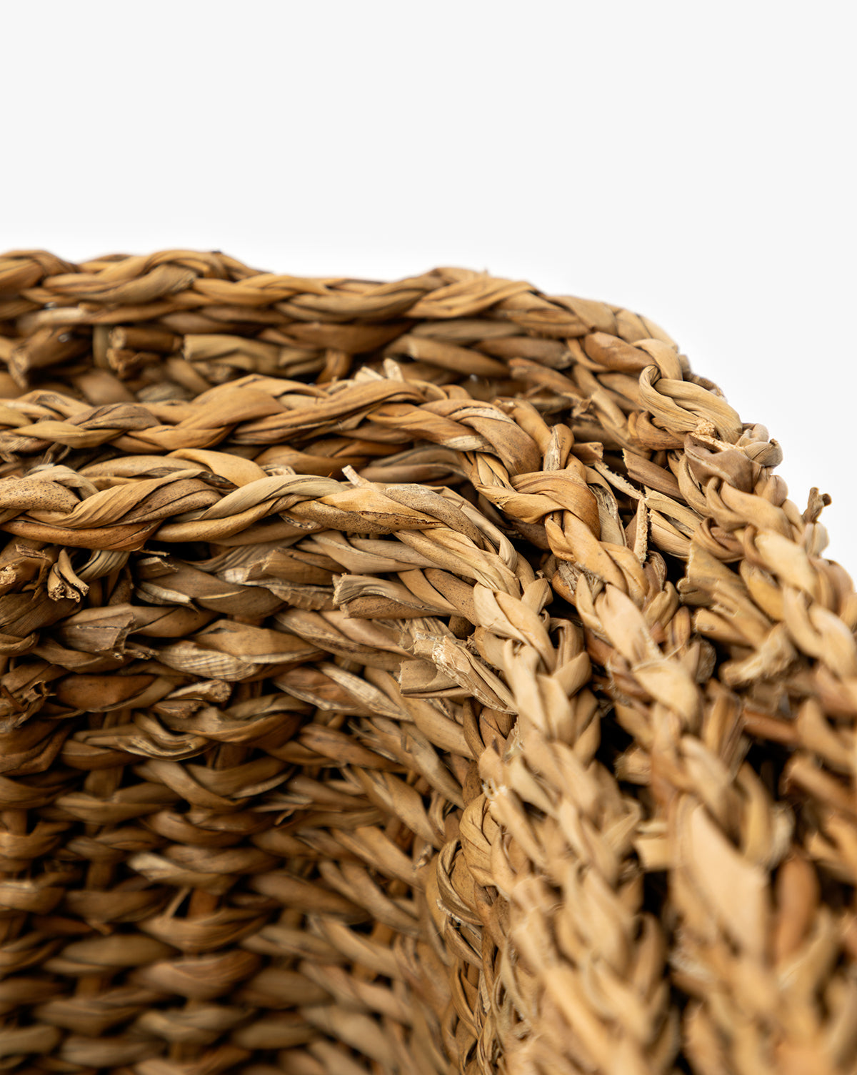 Close-up view of the corner of a Piers Basket (Set of 3), highlighting the detailed texture and natural color of its tightly woven straw fibers against a plain white background, by McGee & Co.