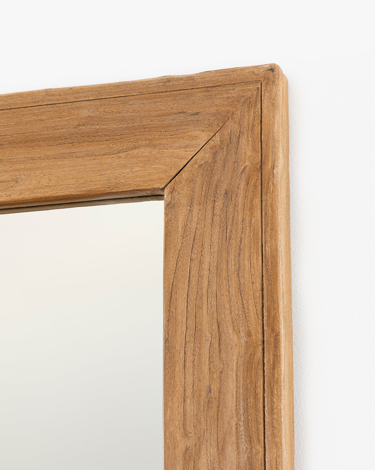 Close-up of the Pippen Floor Mirror’s top right corner, showcasing its honey elm-finished natural wood frame with visible wood grain and mitered joint, set against a white background by McGee & Co.