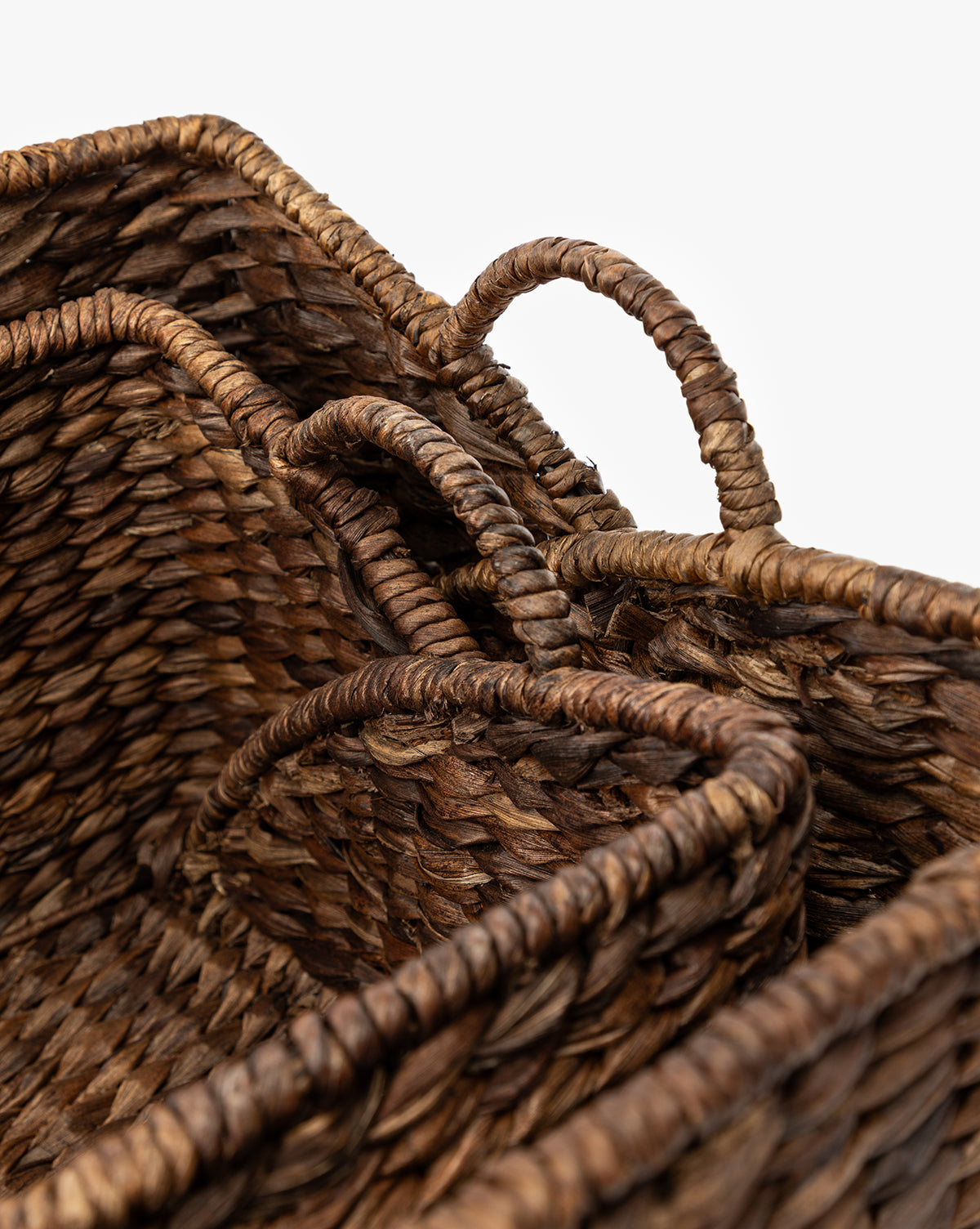 Close-up of two Quimby Baskets, handwoven from natural brown fibers with handles, shown nested together against a white background by McGee & Co.