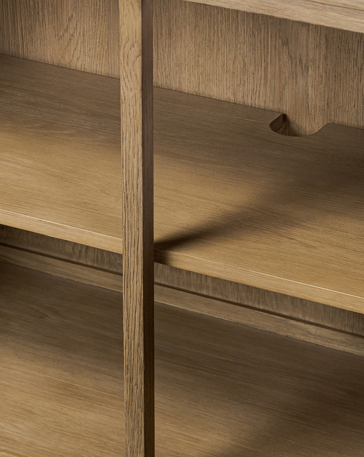 Close-up of the Stonington Oak Sideboard’s wooden shelves with a vertical divider and back cutout notch, highlighting the grain and texture of weathered washed oak—a perfect vintage-inspired detail, by McGee & Co.
