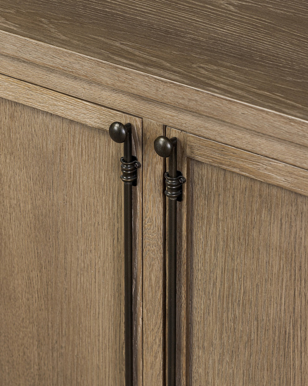 Close-up of two cabinet doors on the Stonington Oak Sideboard, featuring long vertical dark bronze handles and top round knobs. The weathered washed oak showcases a natural light brown grain and vintage-inspired texture, by McGee & Co.