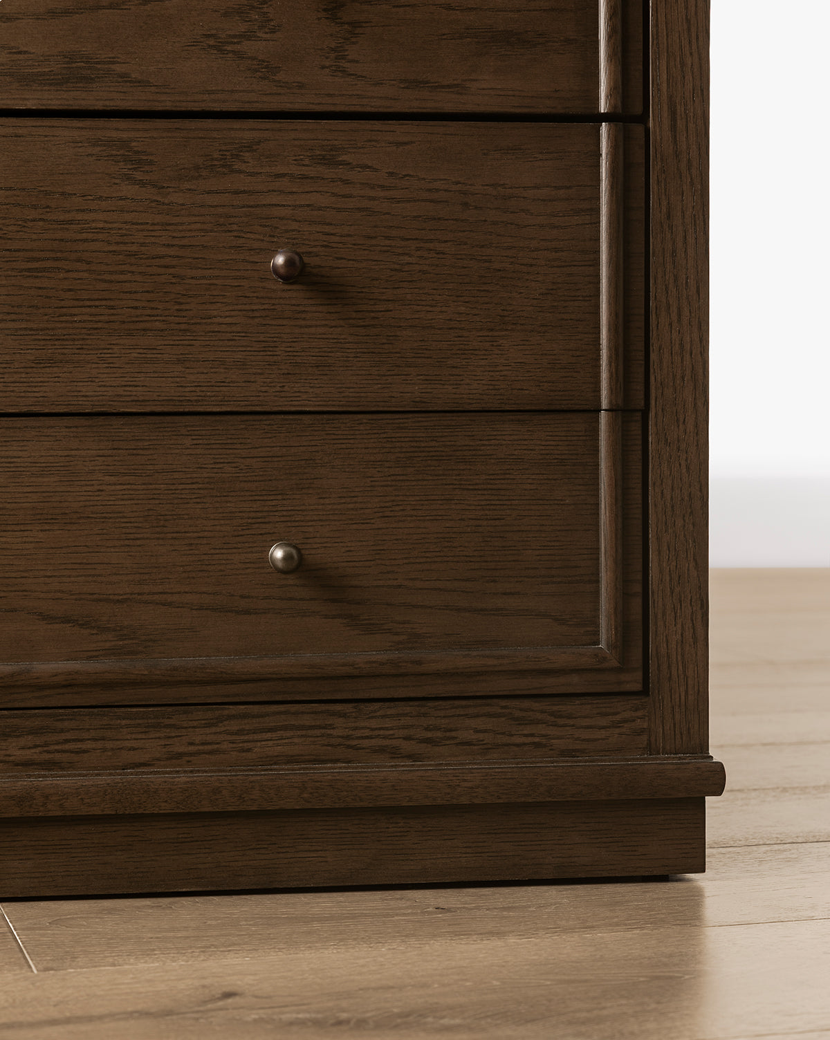 Close-up of the lower section of the Yorkshire Dresser, a bedroom storage piece with two drawers featuring small round metal knobs, standing on a wooden floor, by McGee & Co.